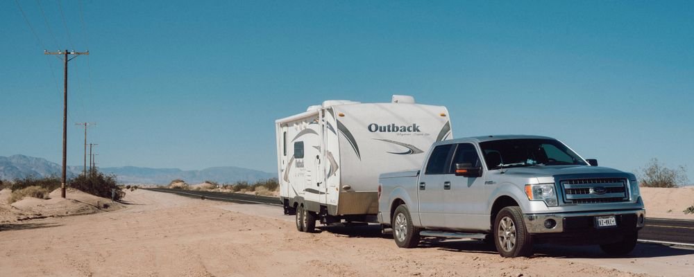 Pickup truck towing a travel trailer on a desert road